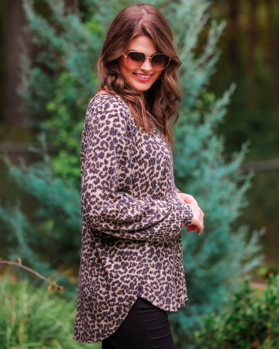 long-sleeve top crafted from soft material with a waffle knit texturing, a round neckline, and a relaxed silhouette that falls into a split hi low rounded hemline on a black leopard pattern fabric and a tan base