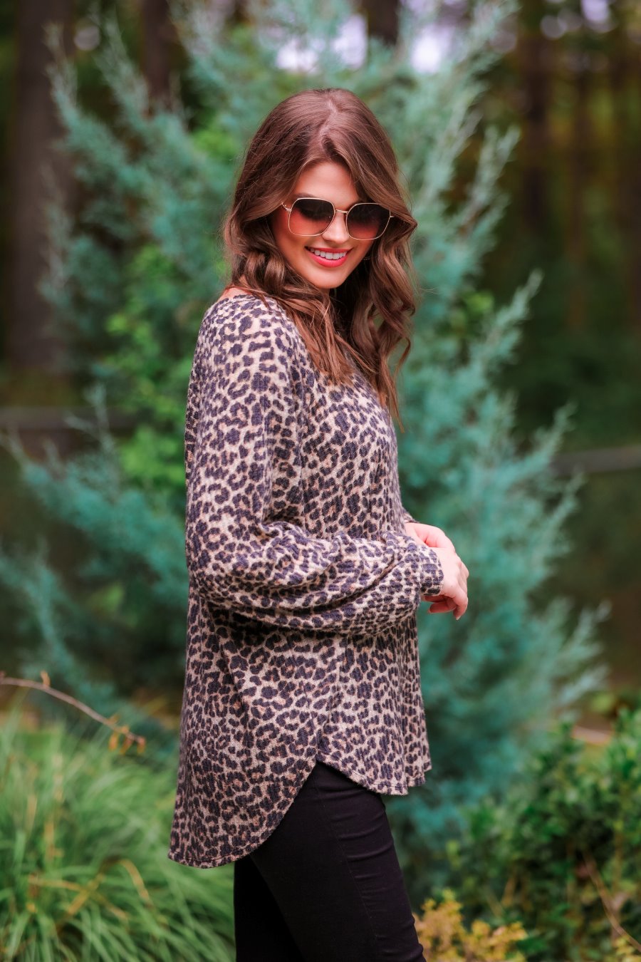 long-sleeve top crafted from soft material with a waffle knit texturing, a round neckline, and a relaxed silhouette that falls into a split hi low rounded hemline on a black leopard pattern fabric and a tan base