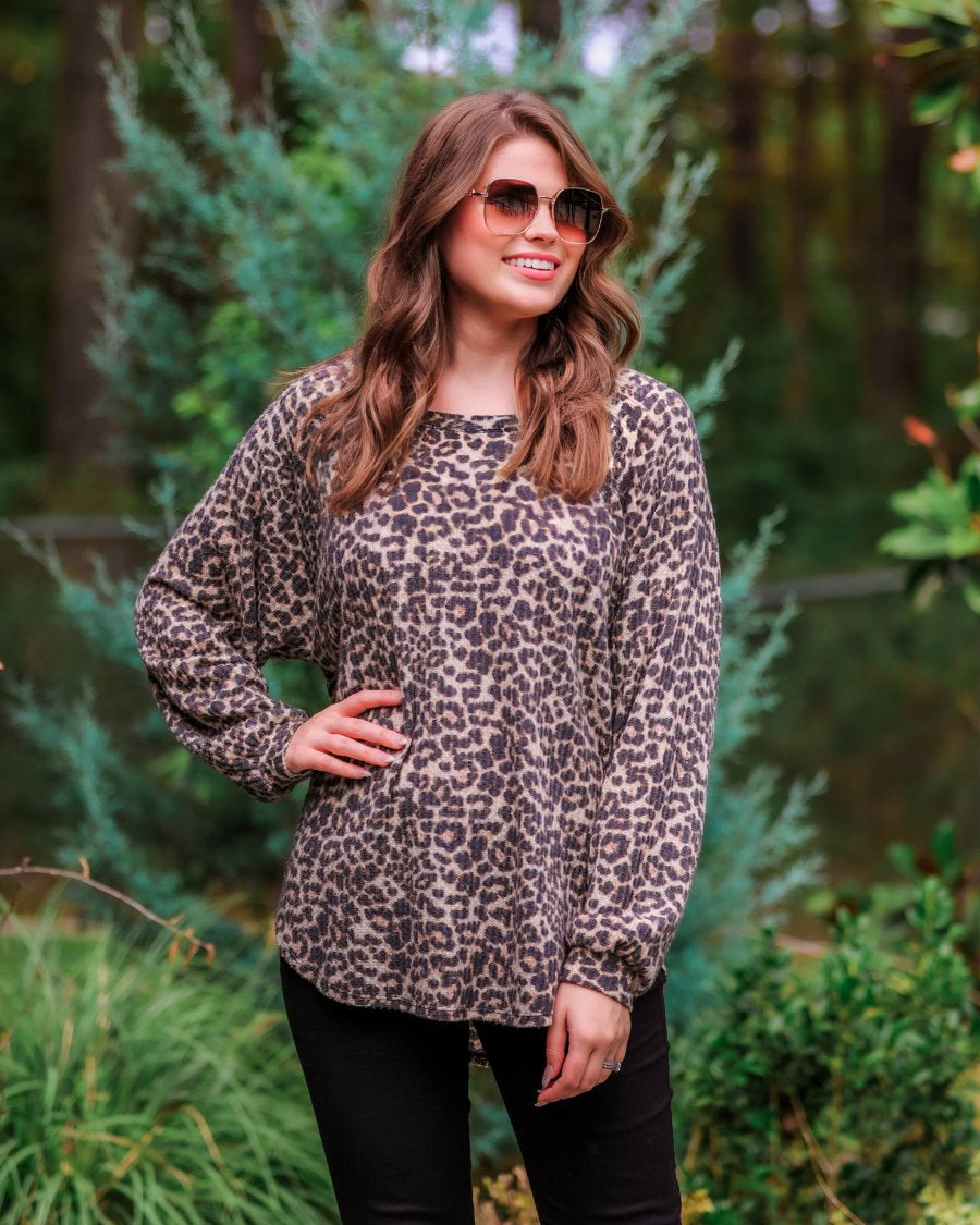 long-sleeve top crafted from soft material with a waffle knit texturing, a round neckline, and a relaxed silhouette that falls into a split hi low rounded hemline on a black leopard pattern fabric and a tan base