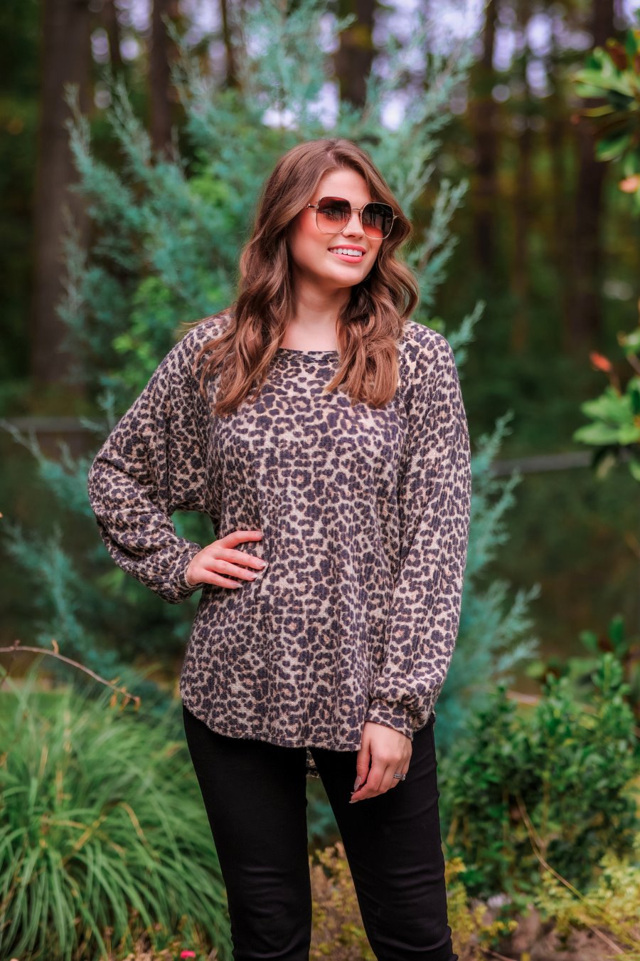 long-sleeve top crafted from soft material with a waffle knit texturing, a round neckline, and a relaxed silhouette that falls into a split hi low rounded hemline on a black leopard pattern fabric and a tan base