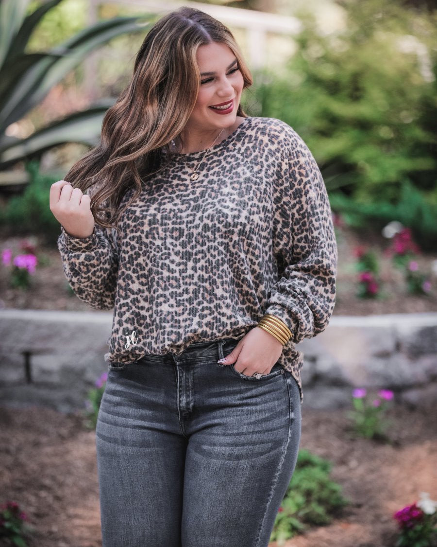 long-sleeve top crafted from soft material with a waffle knit texturing, a round neckline, and a relaxed silhouette that falls into a split hi low rounded hemline on a black leopard pattern fabric and a tan base