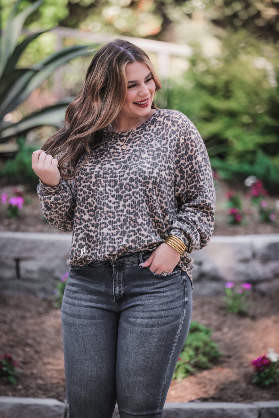 long-sleeve top crafted from soft material with a waffle knit texturing, a round neckline, and a relaxed silhouette that falls into a split hi low rounded hemline on a black leopard pattern fabric and a tan base