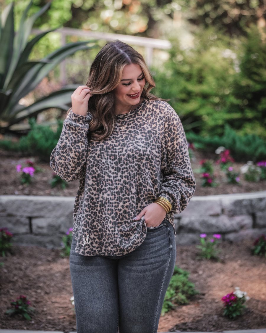long-sleeve top crafted from soft material with a waffle knit texturing, a round neckline, and a relaxed silhouette that falls into a split hi low rounded hemline on a black leopard pattern fabric and a tan base