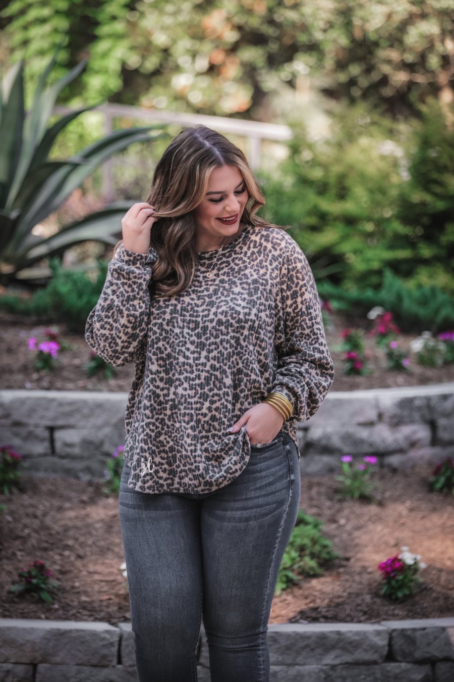 long-sleeve top crafted from soft material with a waffle knit texturing, a round neckline, and a relaxed silhouette that falls into a split hi low rounded hemline on a black leopard pattern fabric and a tan base