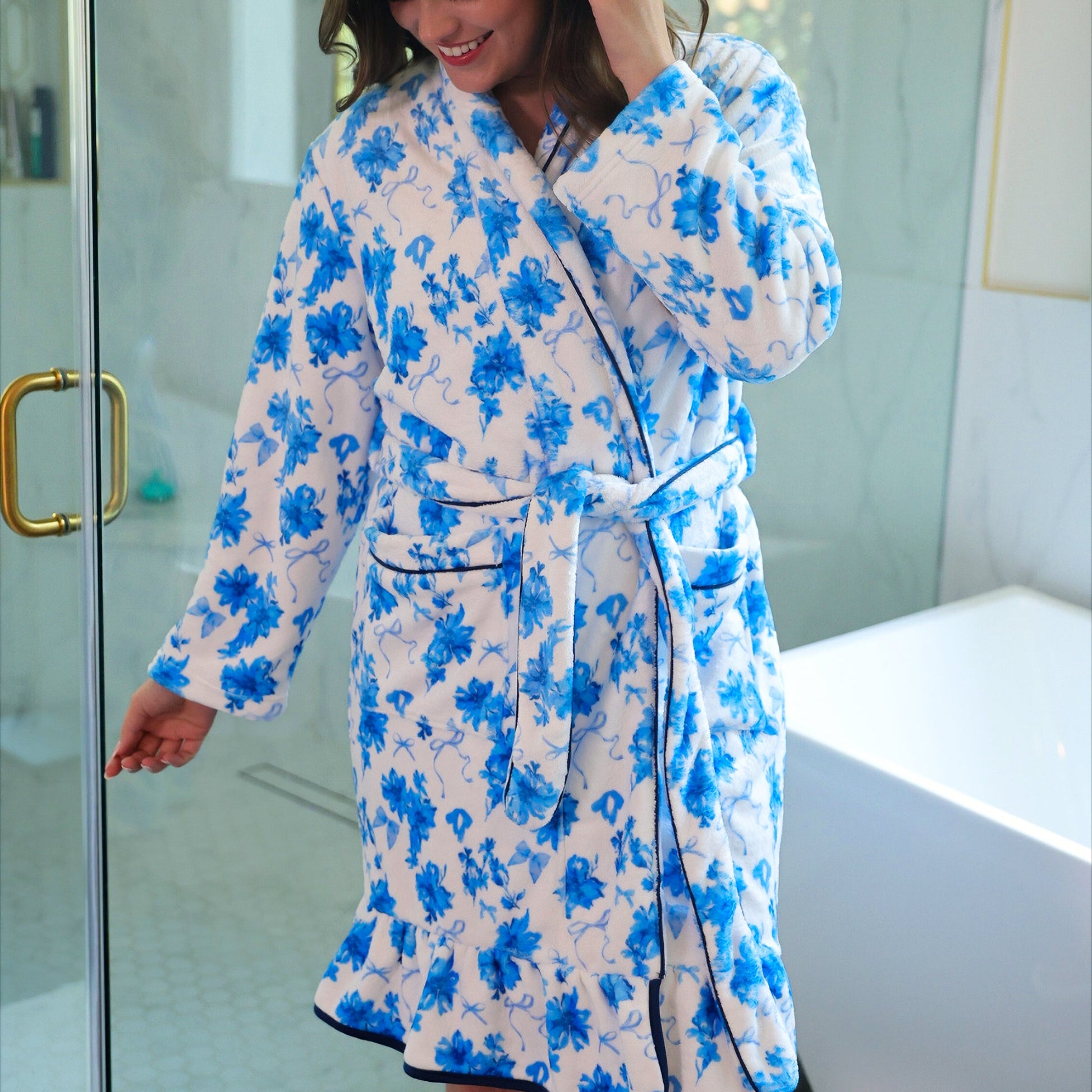 a long sleeve robe with a flattering wrap silhouette, an adjustable waist tie, a playful ruffle hem, and deep patch pockets on ultra plush fabric in Blue Blossom (Blue)