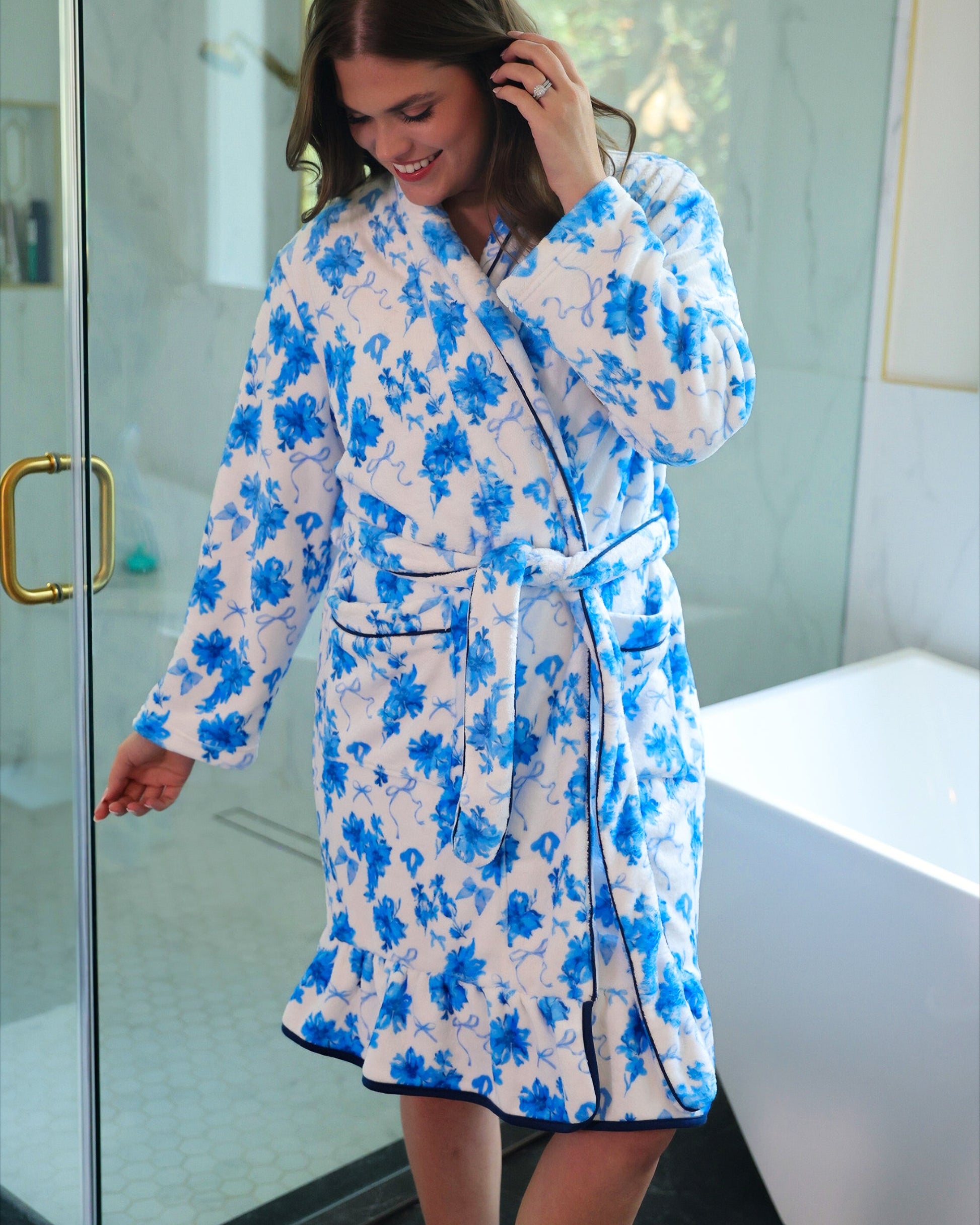 a long sleeve robe with a flattering wrap silhouette, an adjustable waist tie, a playful ruffle hem, and deep patch pockets on ultra plush fabric in Blue Blossom (Blue)