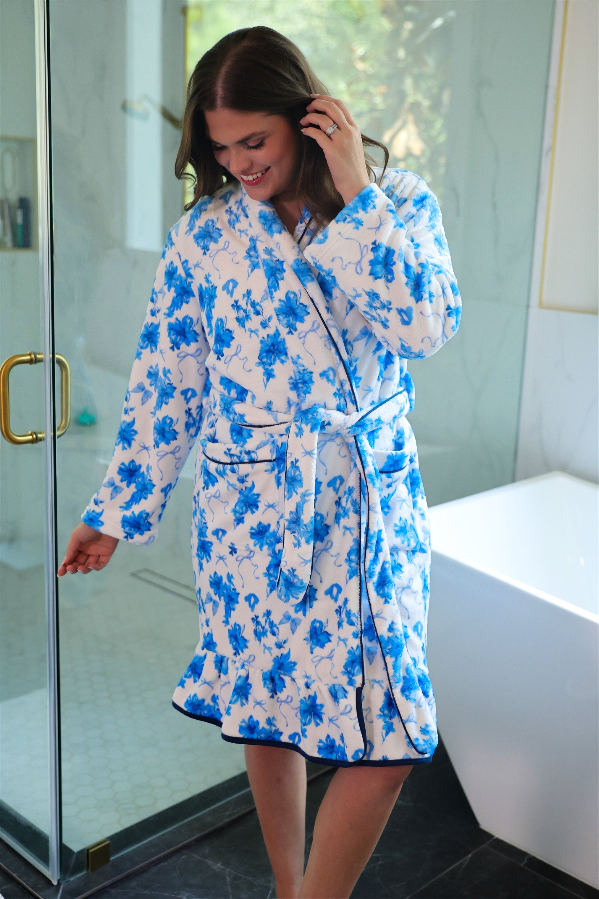 a long sleeve robe with a flattering wrap silhouette, an adjustable waist tie, a playful ruffle hem, and deep patch pockets on ultra plush fabric in Blue Blossom (Blue)