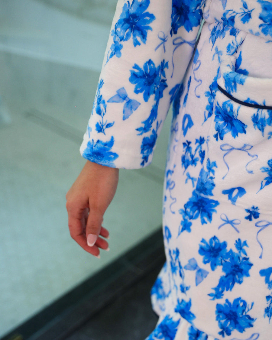 a long sleeve robe with a flattering wrap silhouette, an adjustable waist tie, a playful ruffle hem, and deep patch pockets on ultra plush fabric in Blue Blossom (Blue)