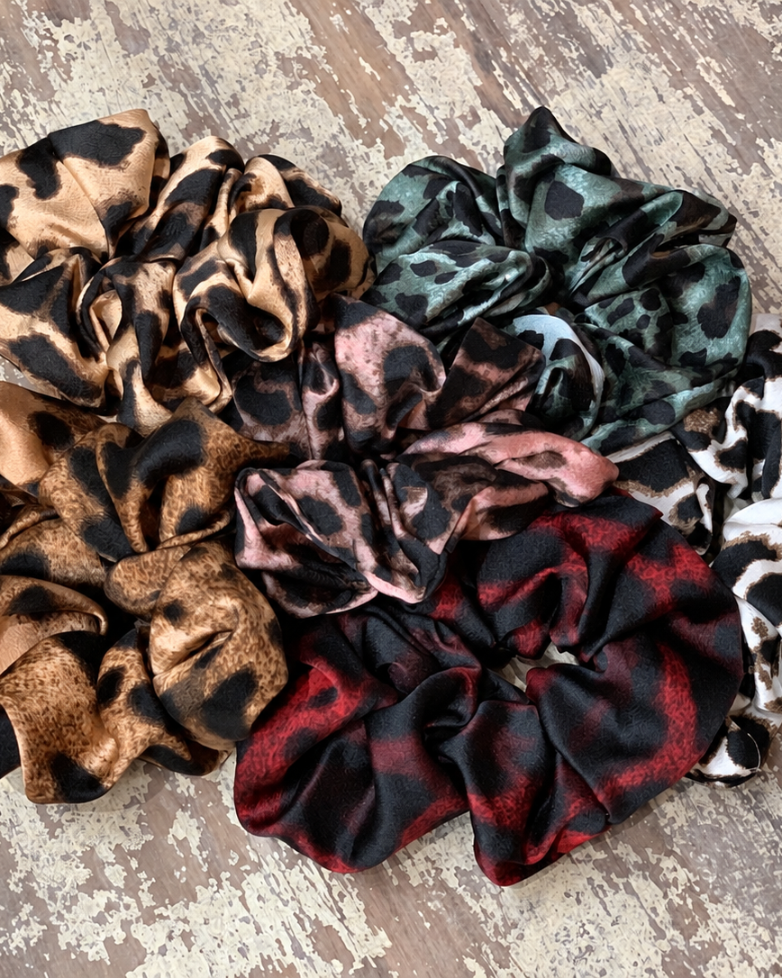 oversized satin-look leopard scrunchies with glossy animal print fabric, plush gathered construction, lightweight feel, and gentle hair-friendly hold in beige, chocolate, mauve, rose, teal, and white