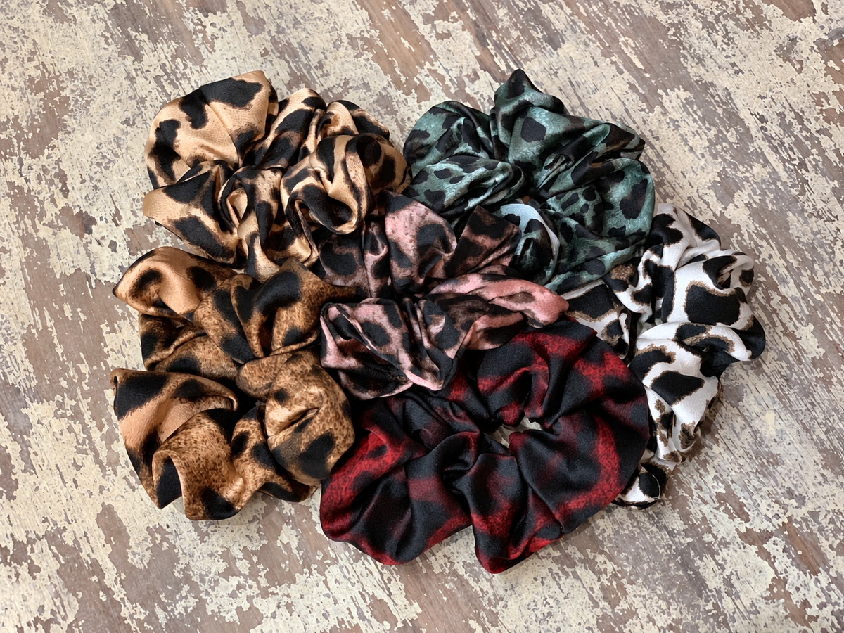 oversized satin-look leopard scrunchies with glossy animal print fabric, plush gathered construction, lightweight feel, and gentle hair-friendly hold in beige, chocolate, mauve, rose, teal, and white