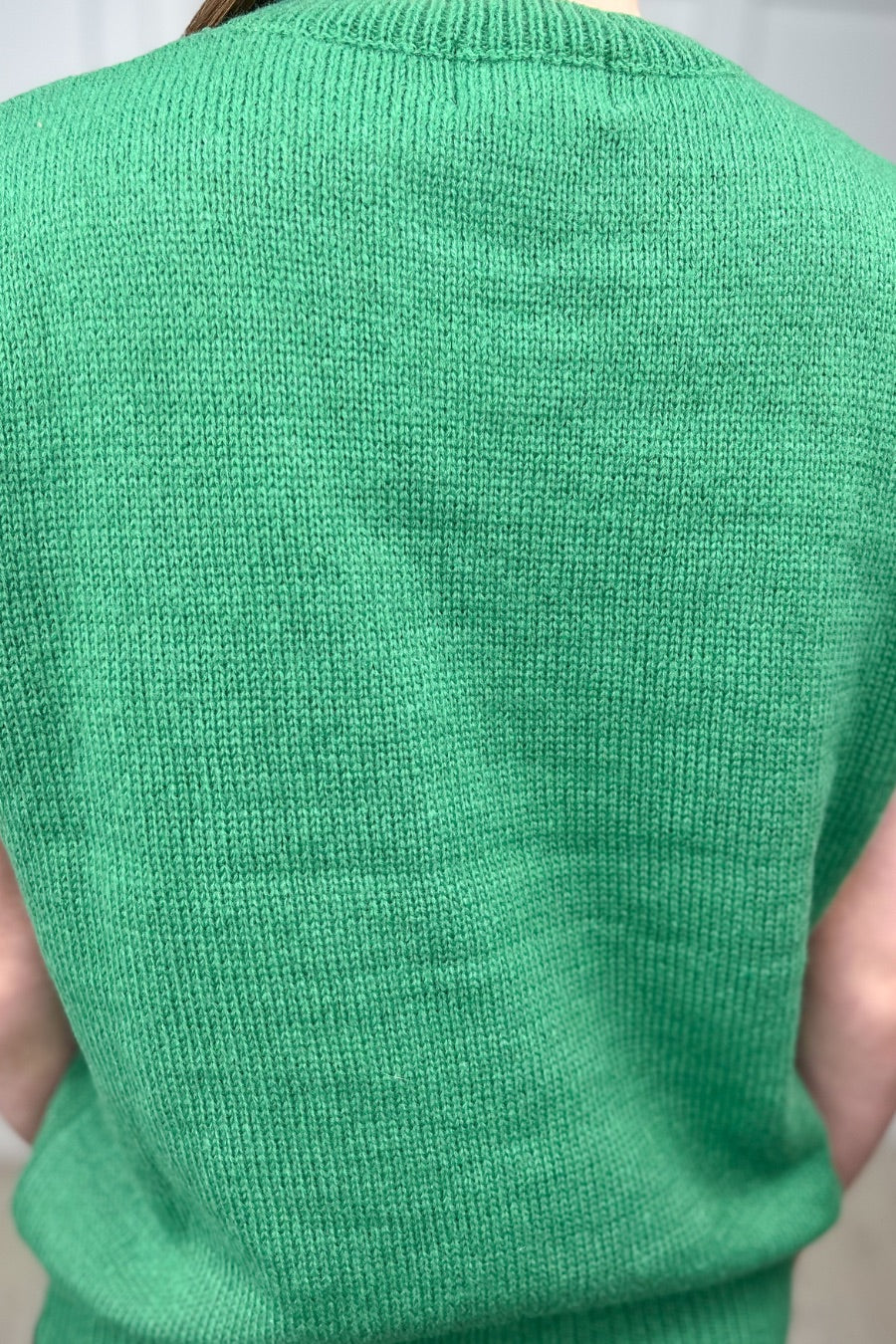 a green soft knit sleeveless seater vest with shimmering 'Lucky' lettering, a relaxed fit, and ribbed collar, cuffs, and hem