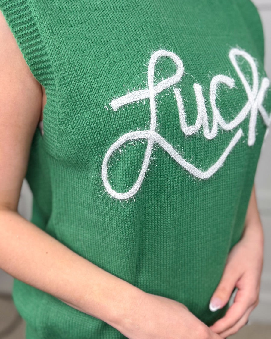 a green soft knit sleeveless seater vest with shimmering 'Lucky' lettering, a relaxed fit, and ribbed collar, cuffs, and hem