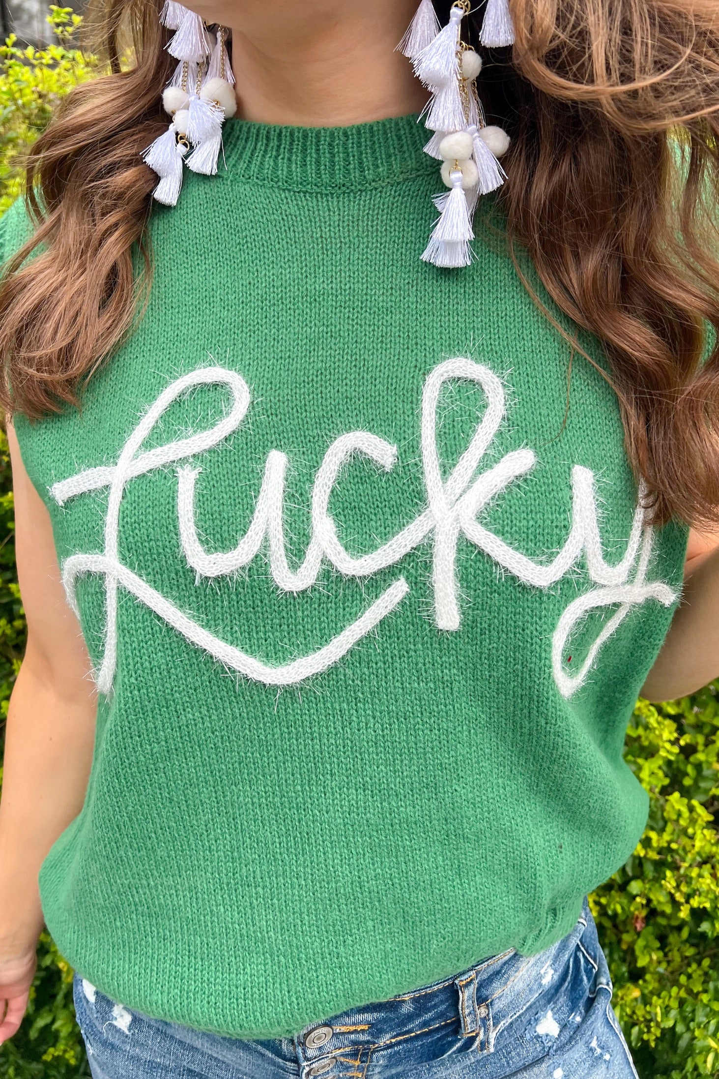 a green soft knit sleeveless seater vest with shimmering 'Lucky' lettering, a relaxed fit, and ribbed collar, cuffs, and hem