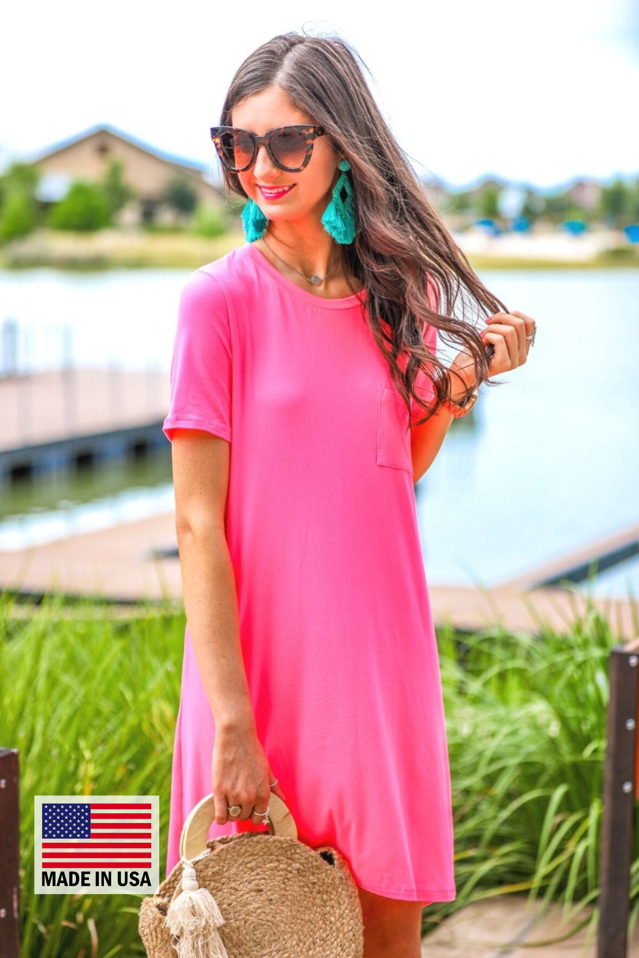 an ultra soft neon pink T-shirt dress with an easy A-line silhouette, short sleeves, a round neckline, a chest pocket, and a straight hemline with MADE IN USA watermark in the bottom left hand corner