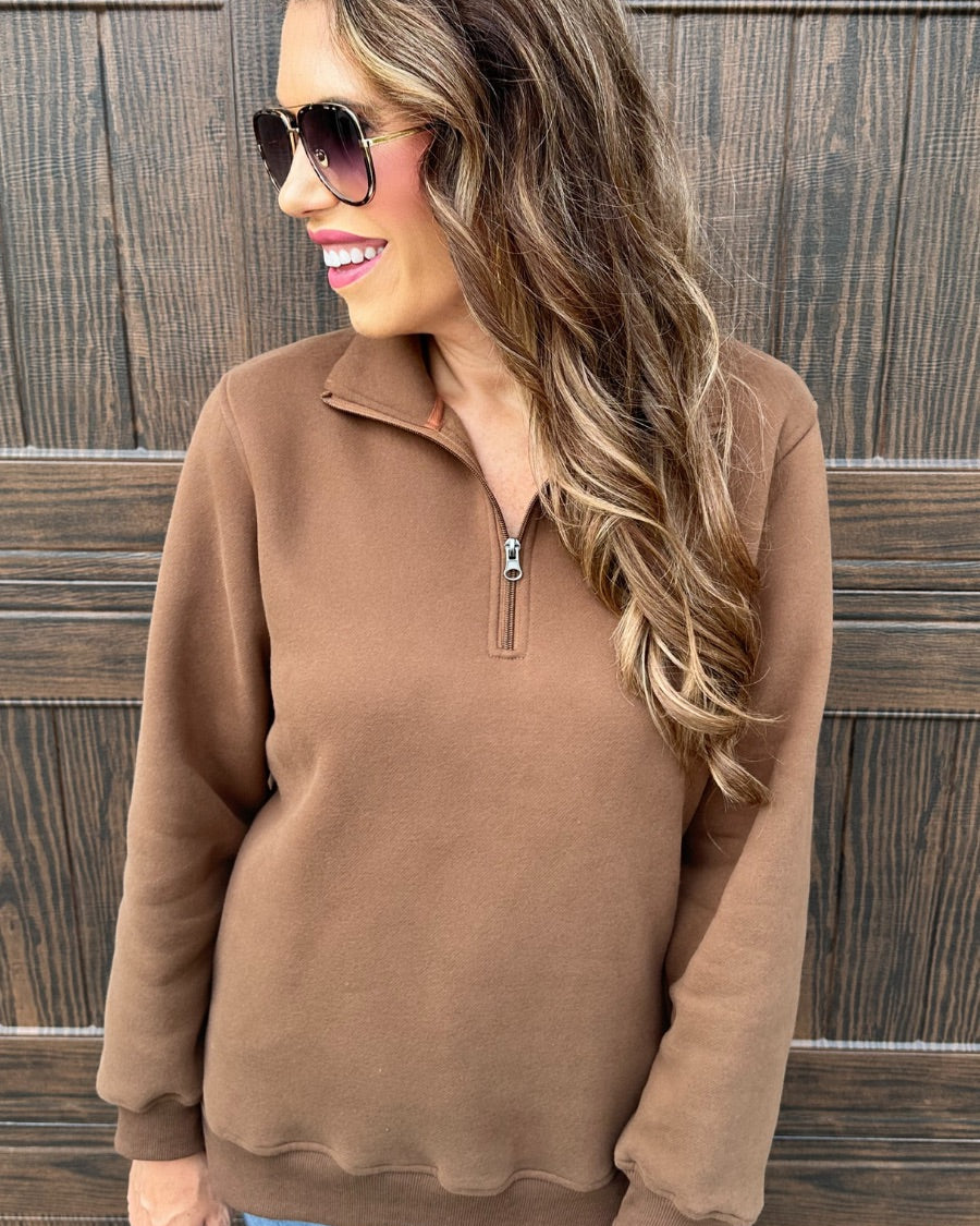a long-sleeve pullover made of cozy fabric with a quarter zip, cuffs, and a split waistband hem in brown