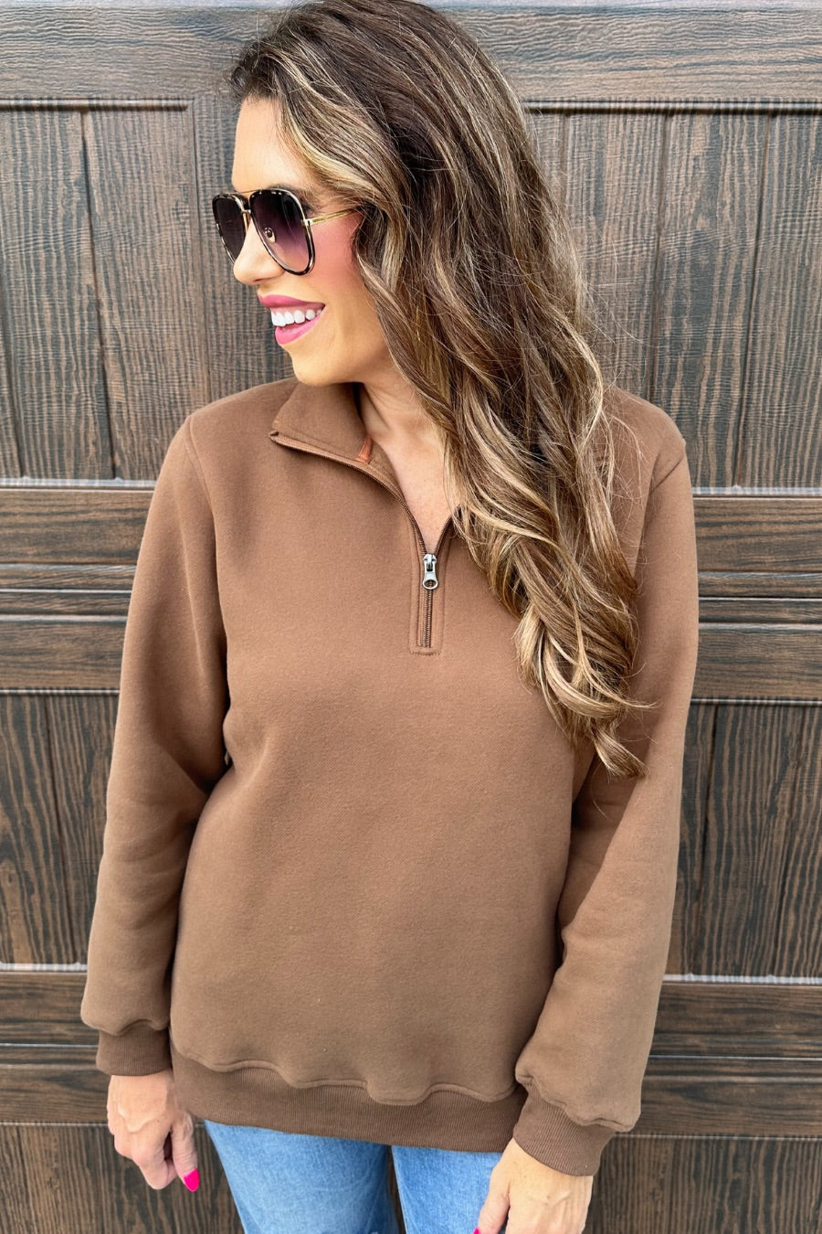 a long-sleeve pullover made of cozy fabric with a quarter zip, cuffs, and a split waistband hem in brown