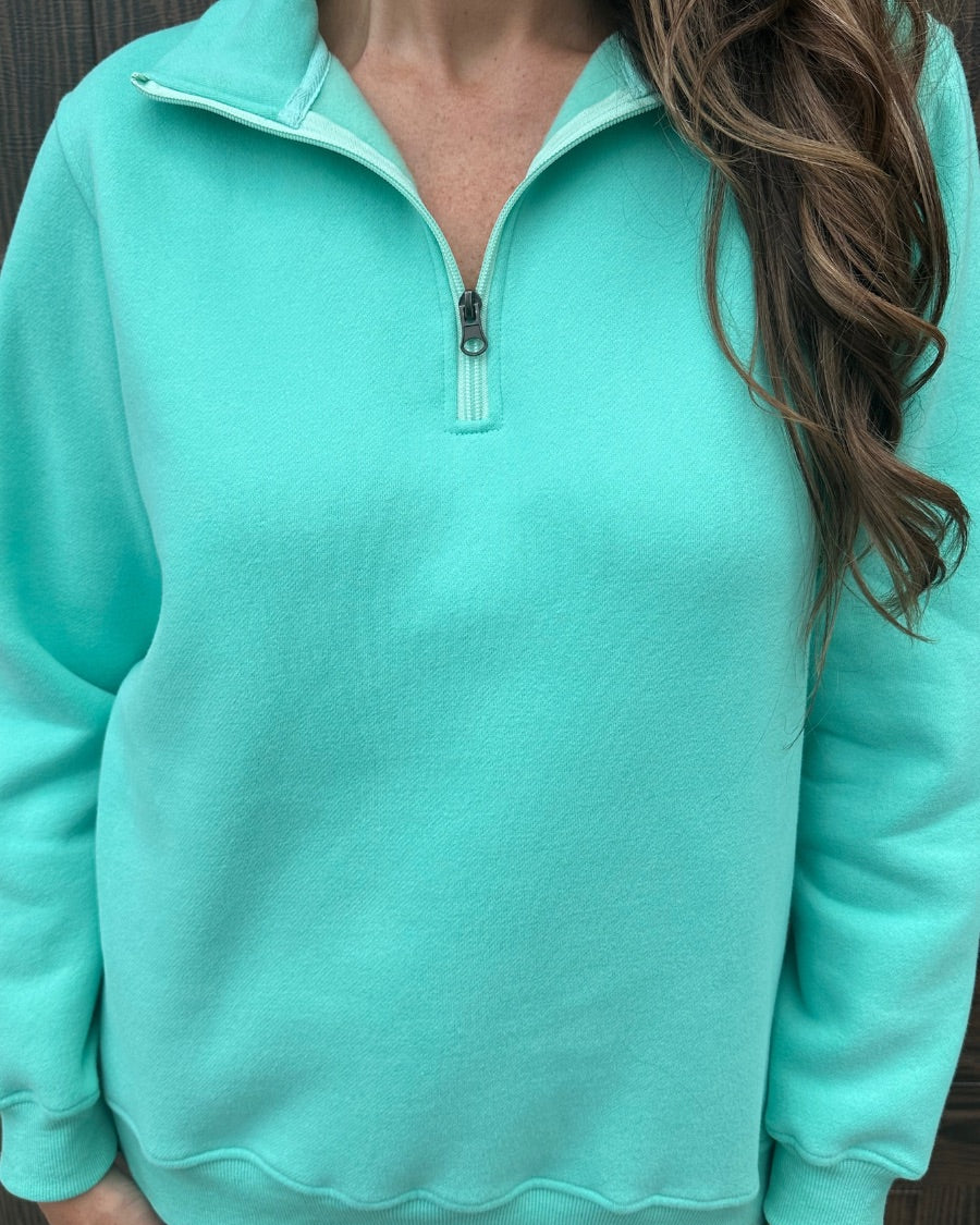 a long-sleeve pullover made of cozy fabric with a quarter zip, cuffs, and a split waistband hem in turquoise