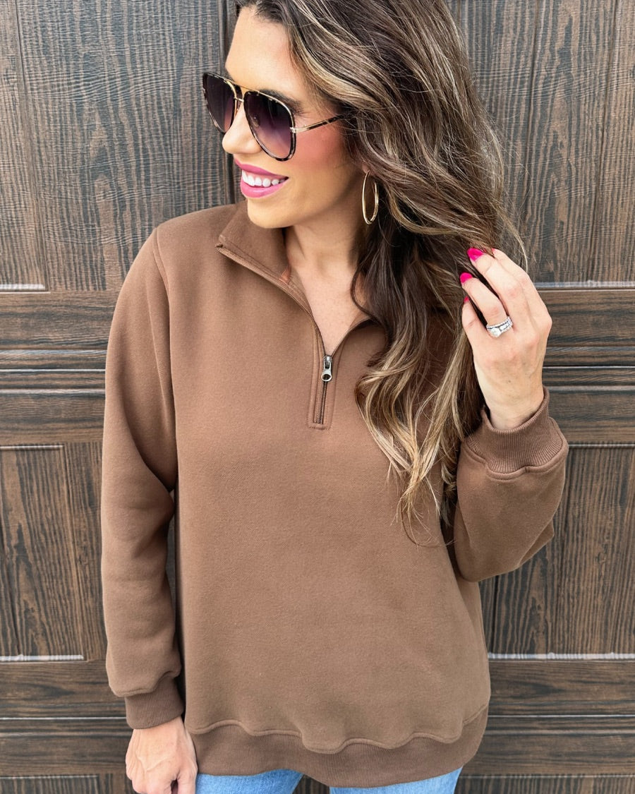 a long-sleeve pullover made of cozy fabric with a quarter zip, cuffs, and a split waistband hem in brown