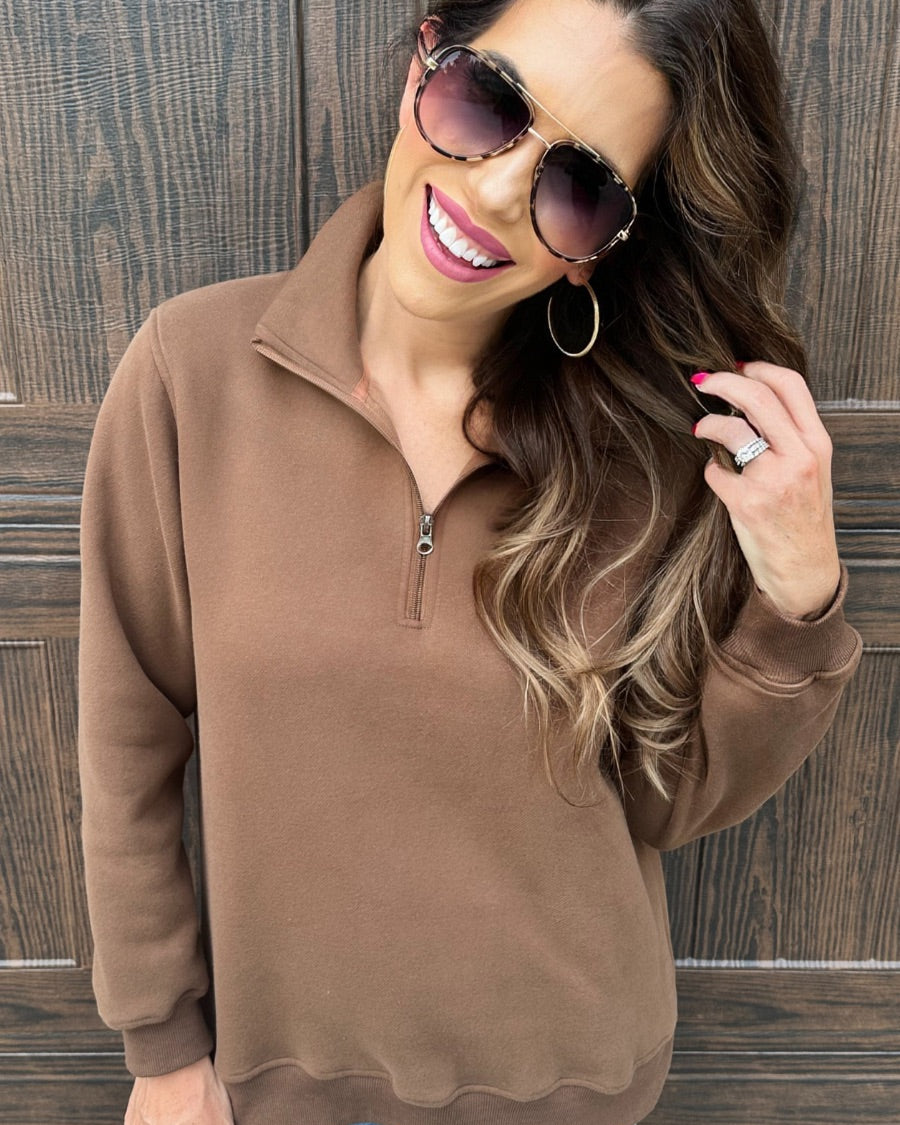 a long-sleeve pullover made of cozy fabric with a quarter zip, cuffs, and a split waistband hem in brown