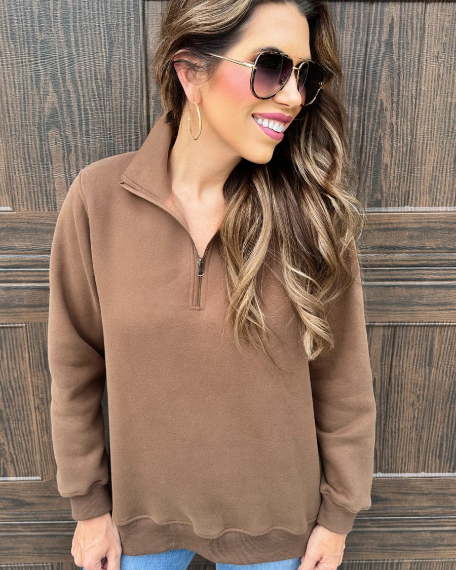 a long-sleeve pullover made of cozy fabric with a quarter zip, cuffs, and a split waistband hem in brown