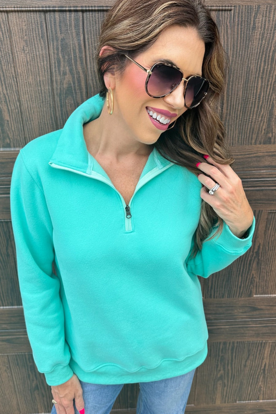 a long-sleeve pullover made of cozy fabric with a quarter zip, cuffs, and a split waistband hem in turquoise