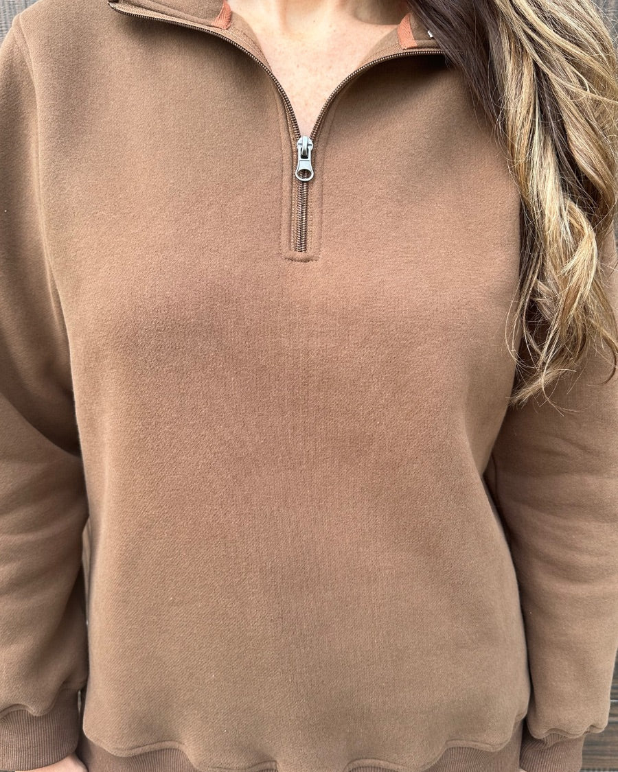 a long-sleeve pullover made of cozy fabric with a quarter zip, cuffs, and a split waistband hem in brown