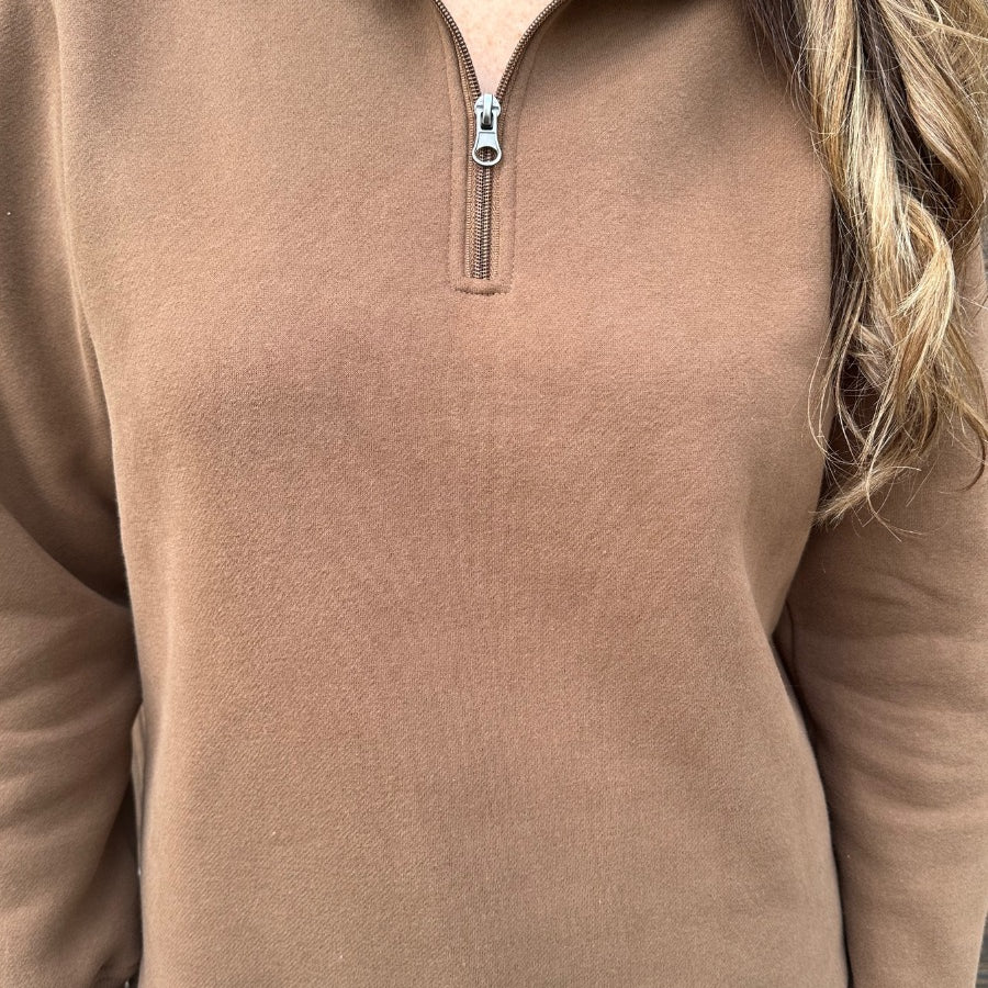 a long-sleeve pullover made of cozy fabric with a quarter zip, cuffs, and a split waistband hem in brown