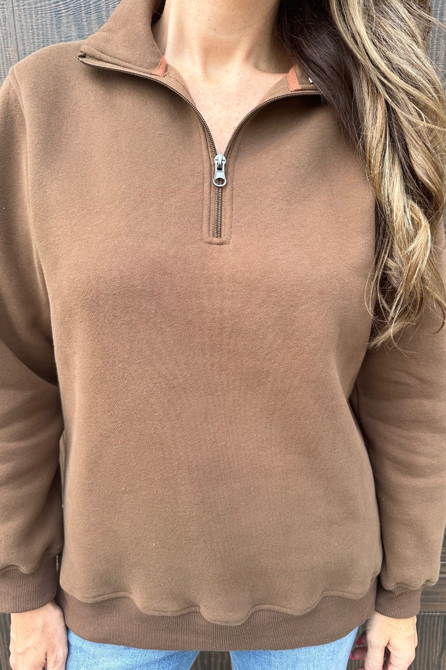 a long-sleeve pullover made of cozy fabric with a quarter zip, cuffs, and a split waistband hem in brown