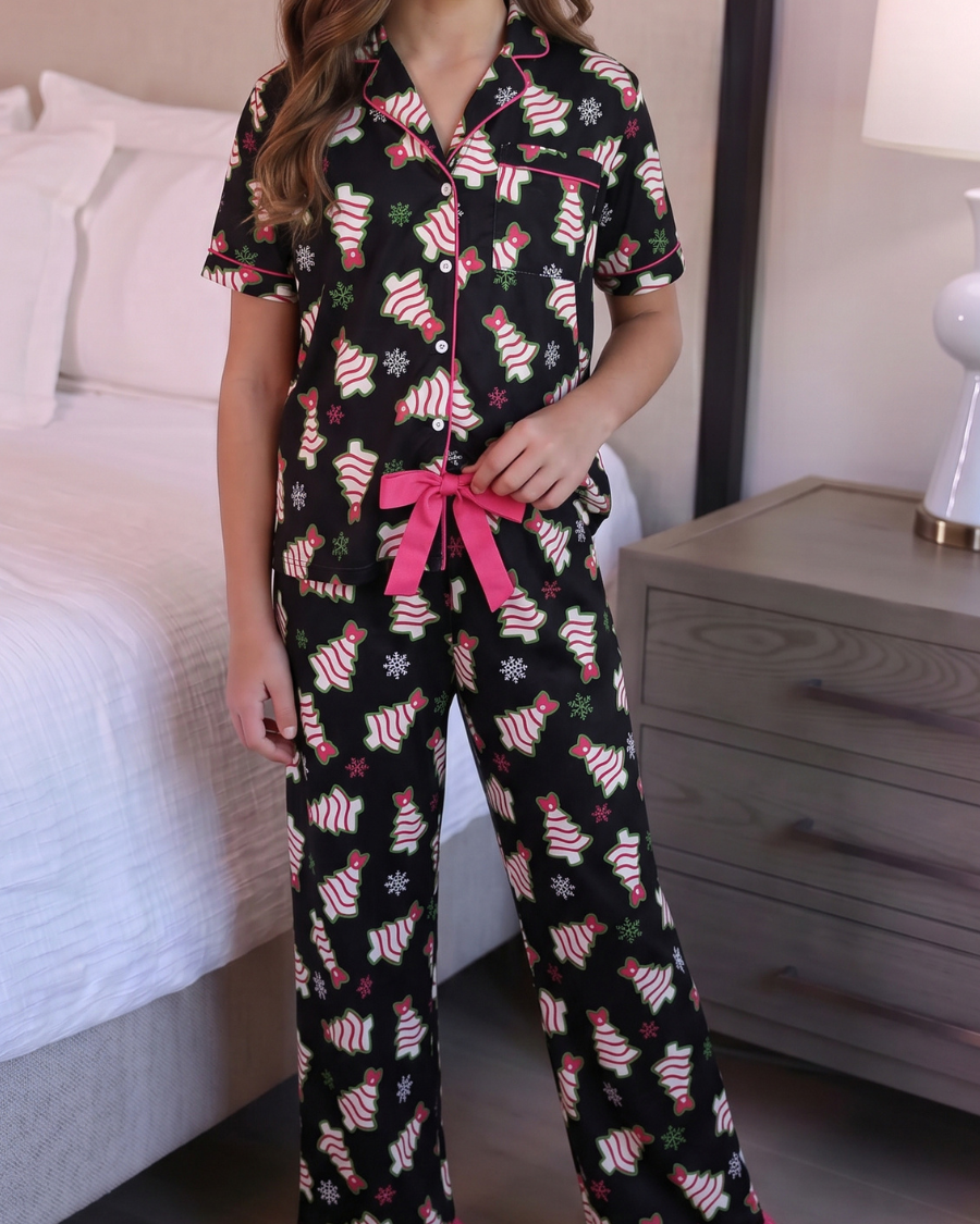 Young girl wearing a black pajama set with pink accents in a bedroom.