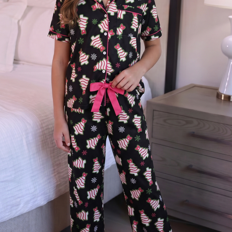 Young girl wearing a black pajama set with pink accents in a bedroom.