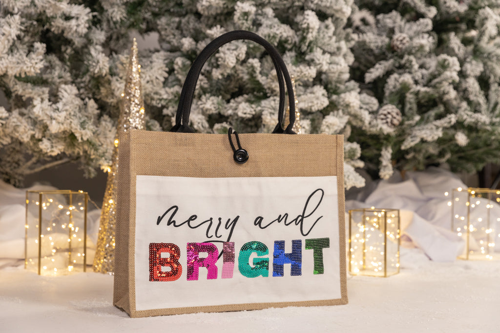 burlap construction bag with a velcro front pocket, handles, & button closure with embroidered "Merry and" on the top line & dazzling multi-color sequin "Bright" lettering on bottom line