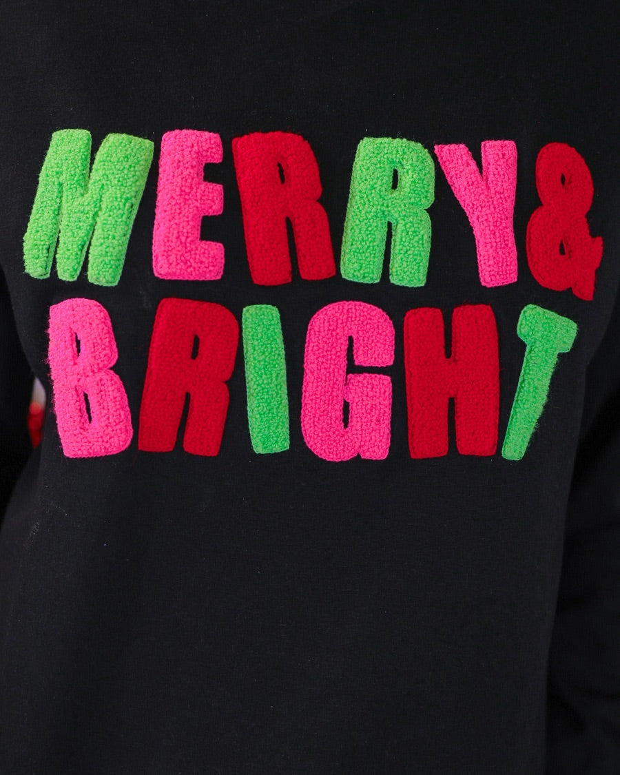 black long-sleeve sweatshirt with stitched chenille patches that spell out MERRY BRIGHT with an ampersand in between in alternating green, pink, and red on our new luxe material