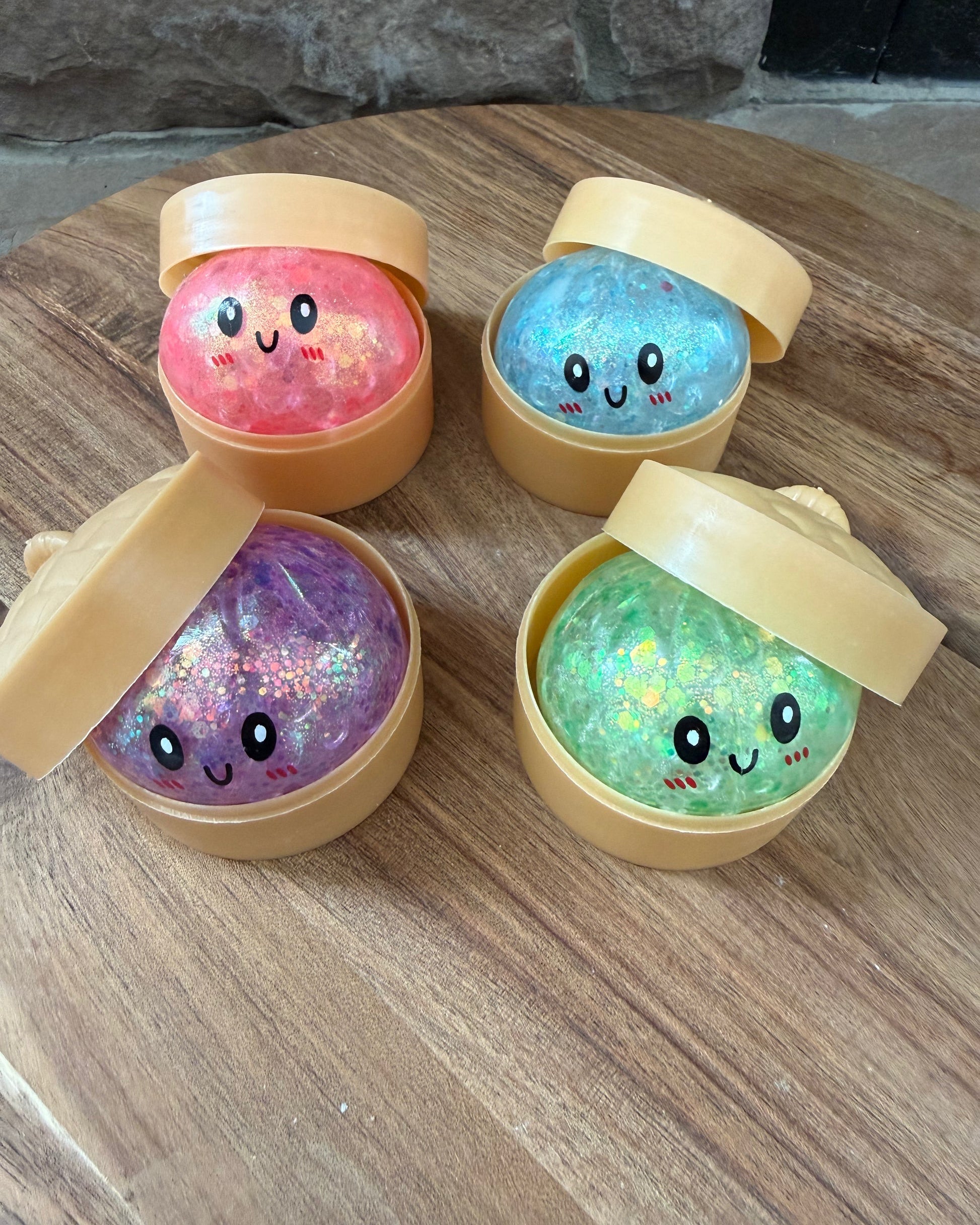 a mystery bead-filled mini dumpling squishy with assorted colors, iridescent shimmer, kawaii face, steamer-style container, and soft sensory texture in blue, green, pink, and purple