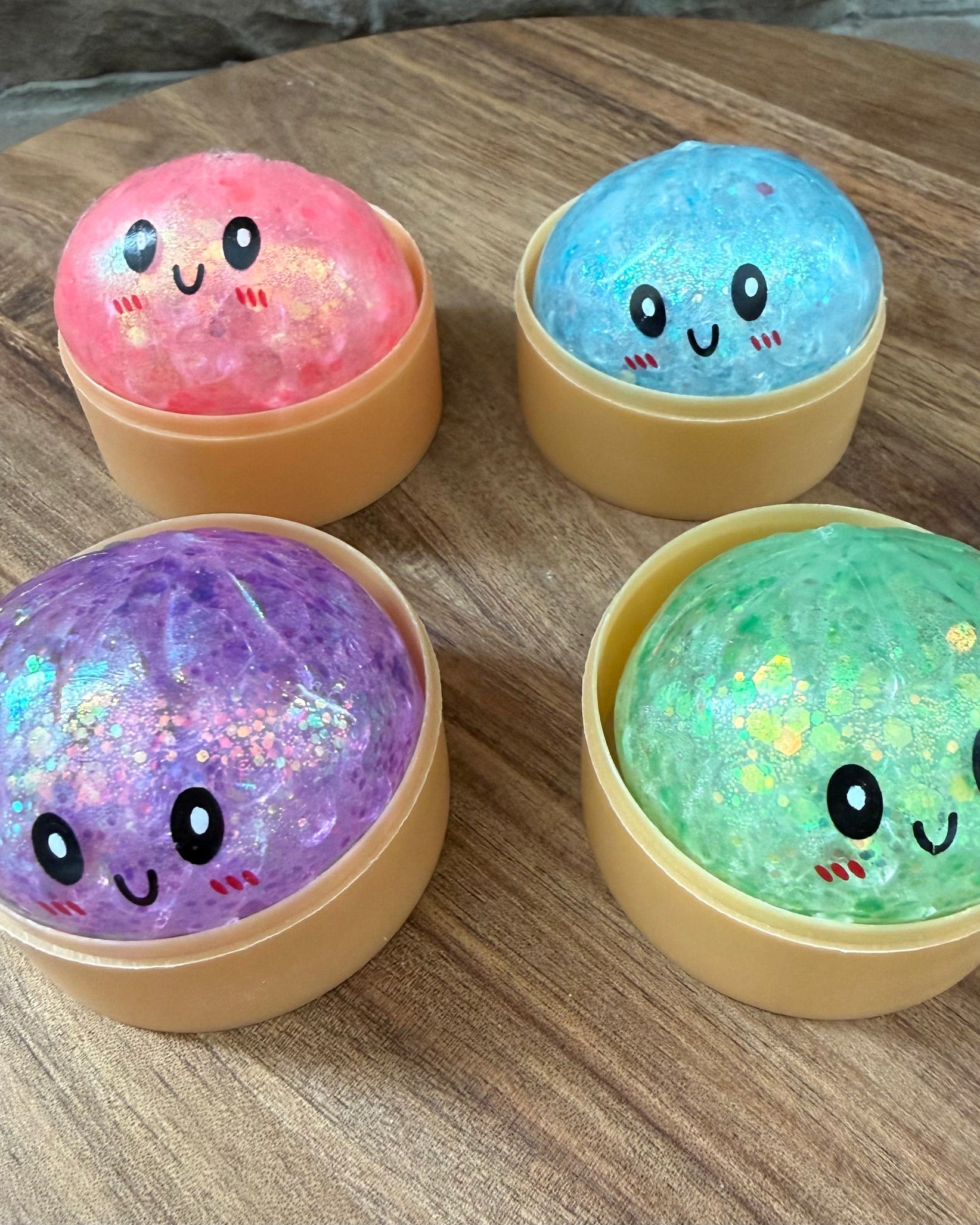 a mystery bead-filled mini dumpling squishy with assorted colors, iridescent shimmer, kawaii face, steamer-style container, and soft sensory texture in blue, green, pink, and purple