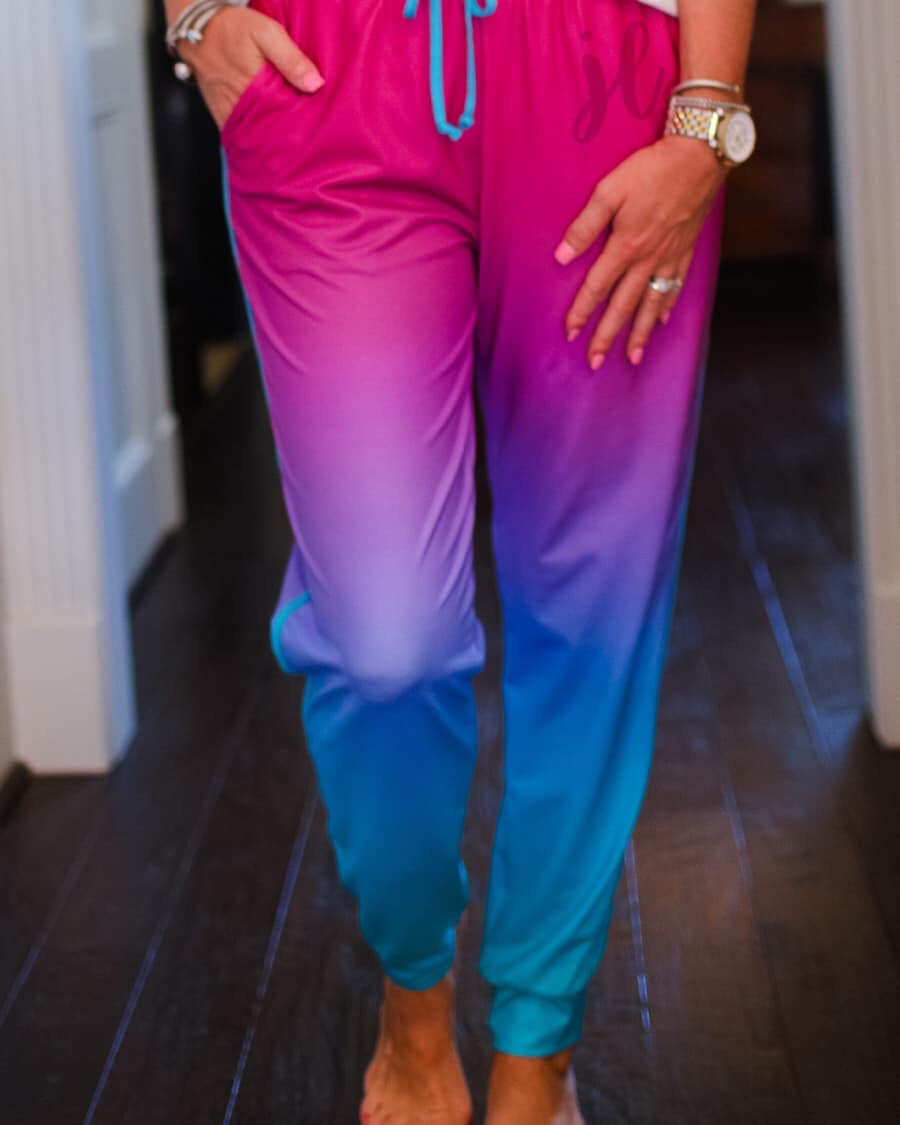 relaxed fit mid-rise joggers with side pockets and a tie waist drawstring, designed on a magenta to turquoise ombré print fabric with turquoise trim