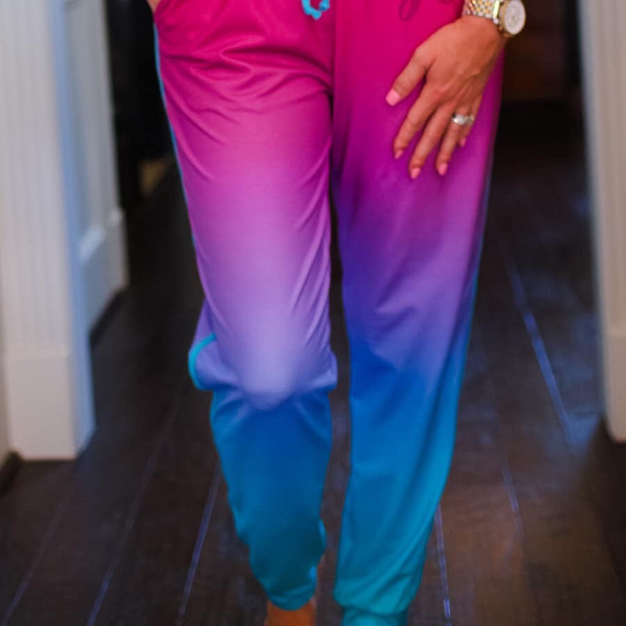 relaxed fit mid-rise joggers with side pockets and a tie waist drawstring, designed on a magenta to turquoise ombré print fabric with turquoise trim