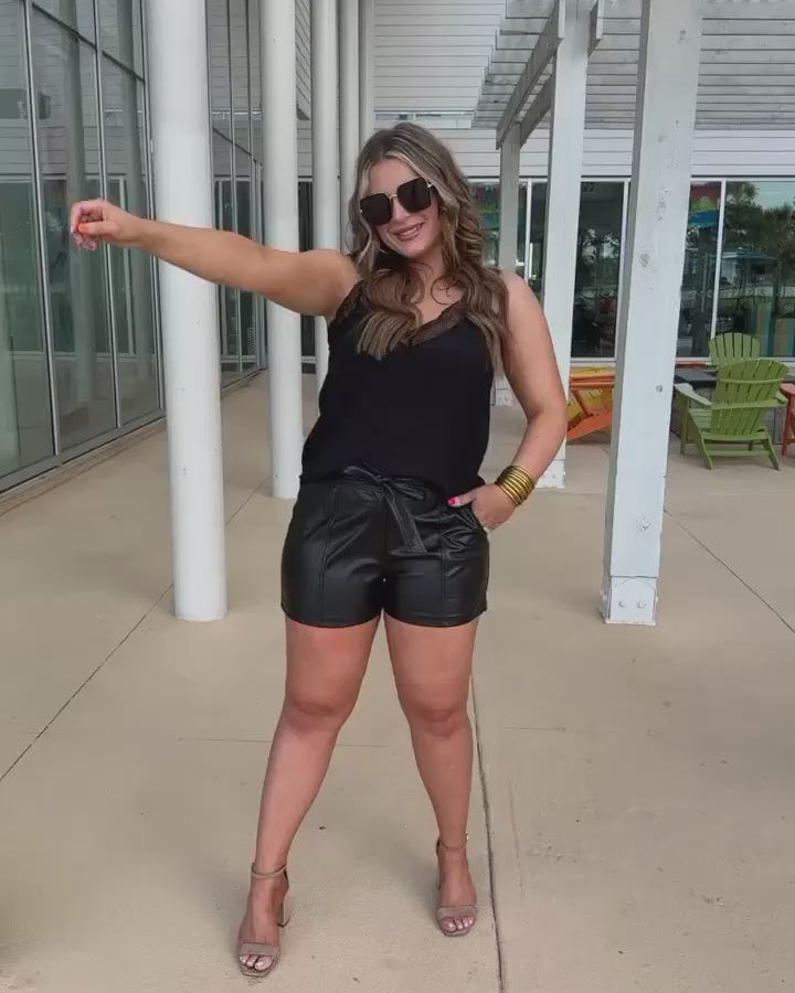 sleek faux leather shorts with zip and button closure, side pockets, a non-removable tie detail, and an elastic back waistband in black