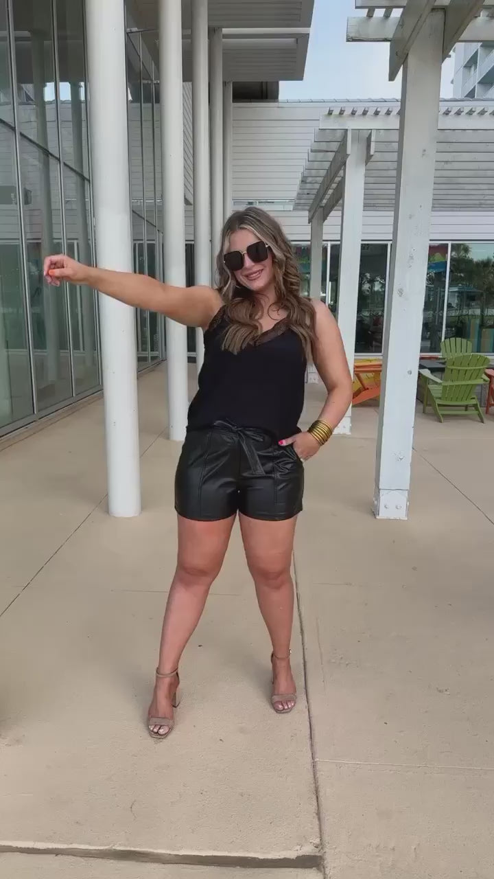 sleek faux leather shorts with zip and button closure, side pockets, a non-removable tie detail, and an elastic back waistband in black