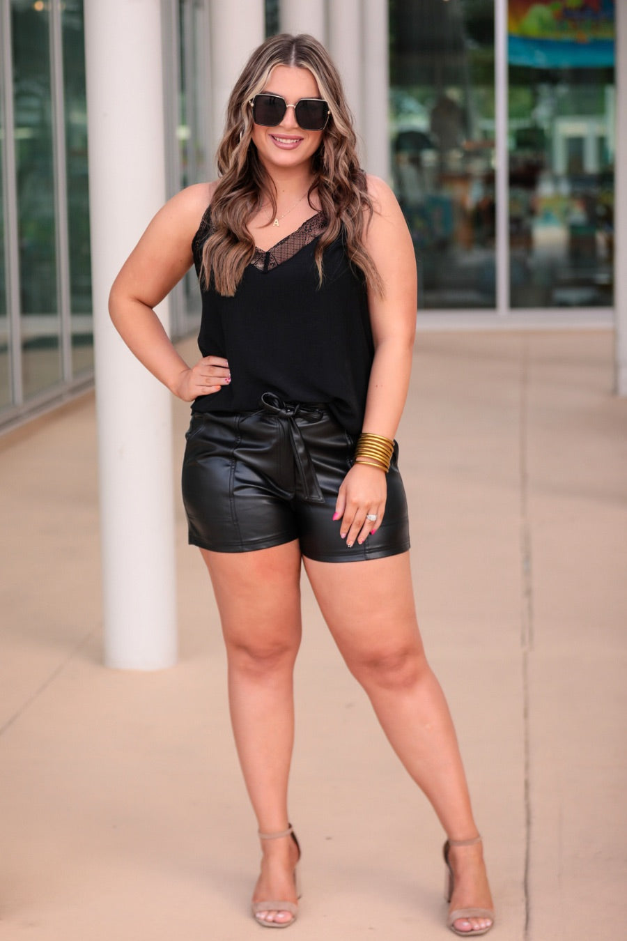 sleek faux leather shorts with zip and button closure, side pockets, a non-removable tie detail, and an elastic back waistband in black