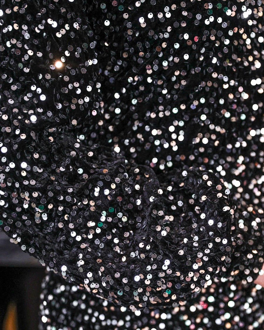 a black long balloon sleeve dress made of sparkly allover sequins, luxe velvet underlay, a keyhole accented upper back with button closure, a round neckline, and subtle elastic cuffs