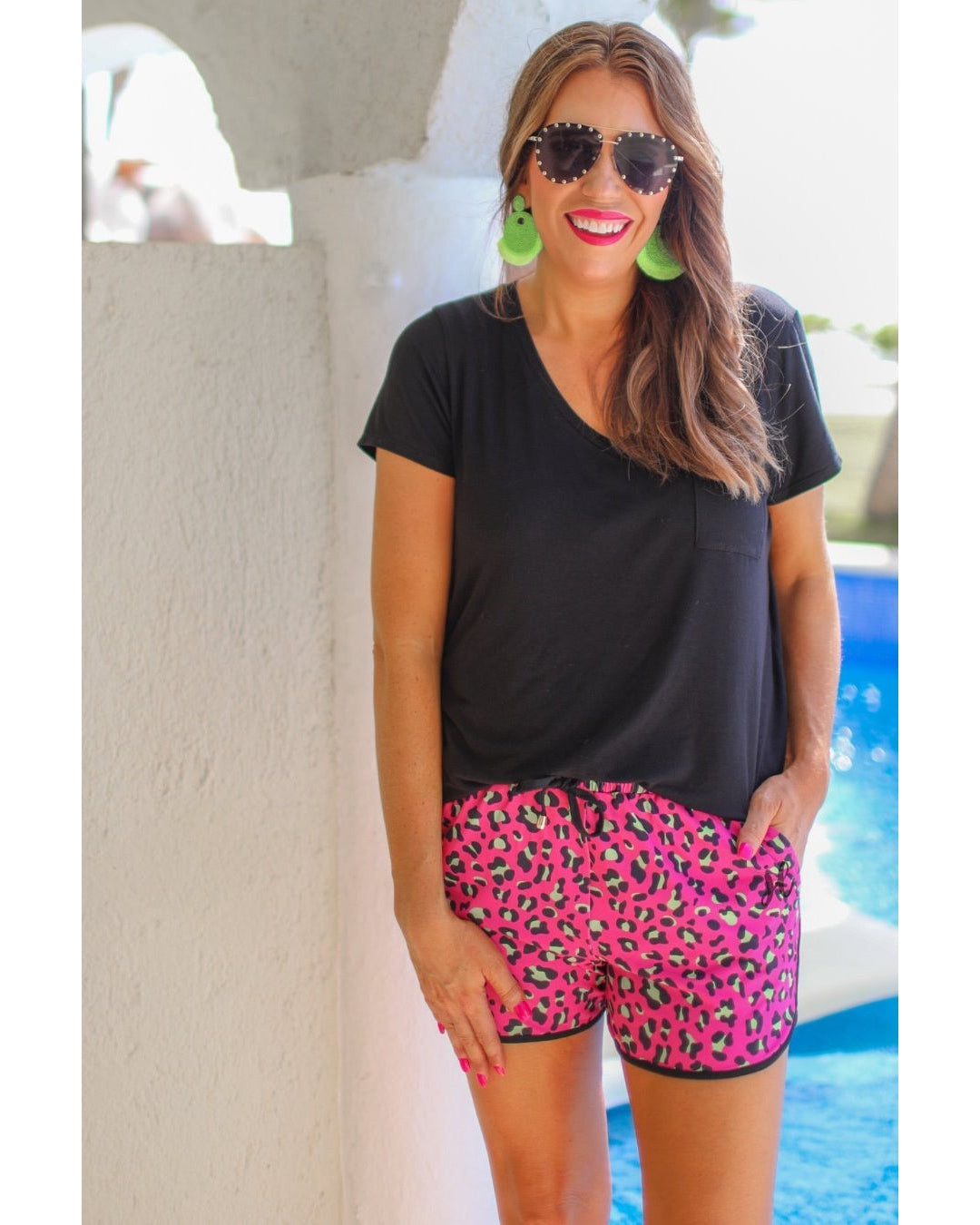 mid-rise relaxed fit activewear shorts with side pockets and a tie waist drawstring with gold bead accents, designed on a leopard print fabric, hot pink base, and black trim