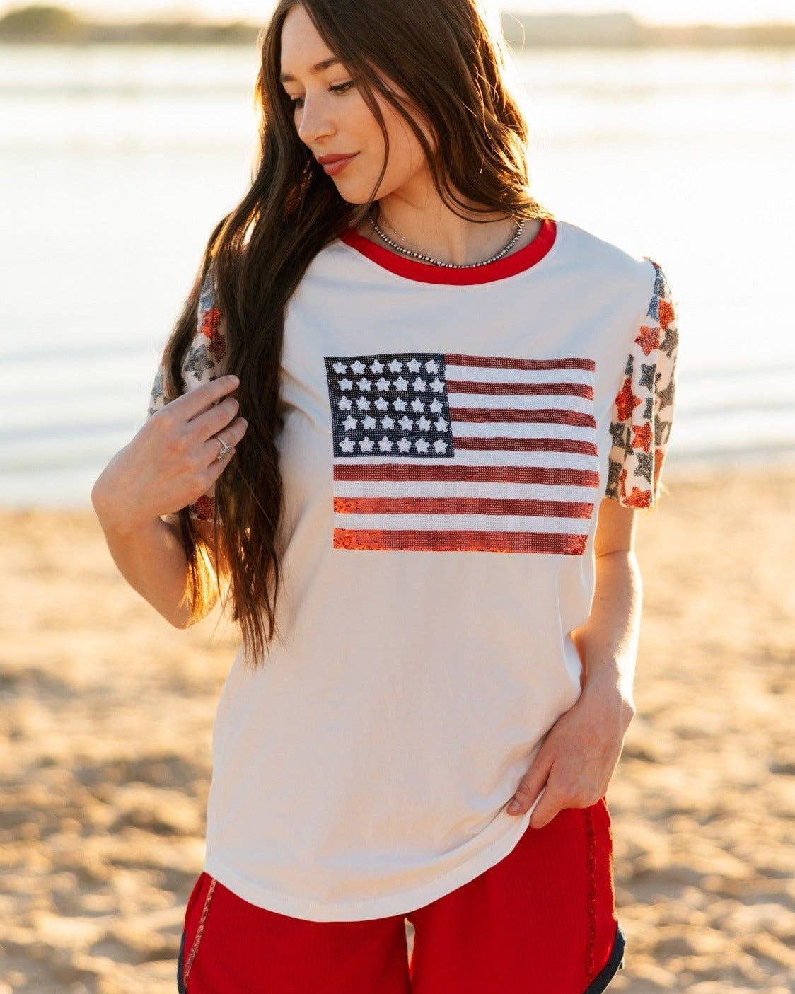 a high-stretch roomy-fit crew neck top with a sequin American flag front, lined star sleeves (red, white, and blue), red neckline trim, and a comfortable fit that runs large