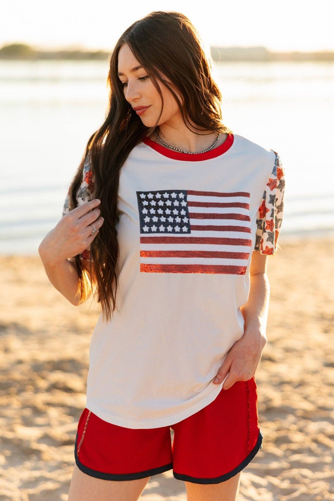 a high-stretch roomy-fit crew neck top with a sequin American flag front, lined star sleeves (red, white, and blue), red neckline trim, and a comfortable fit that runs large