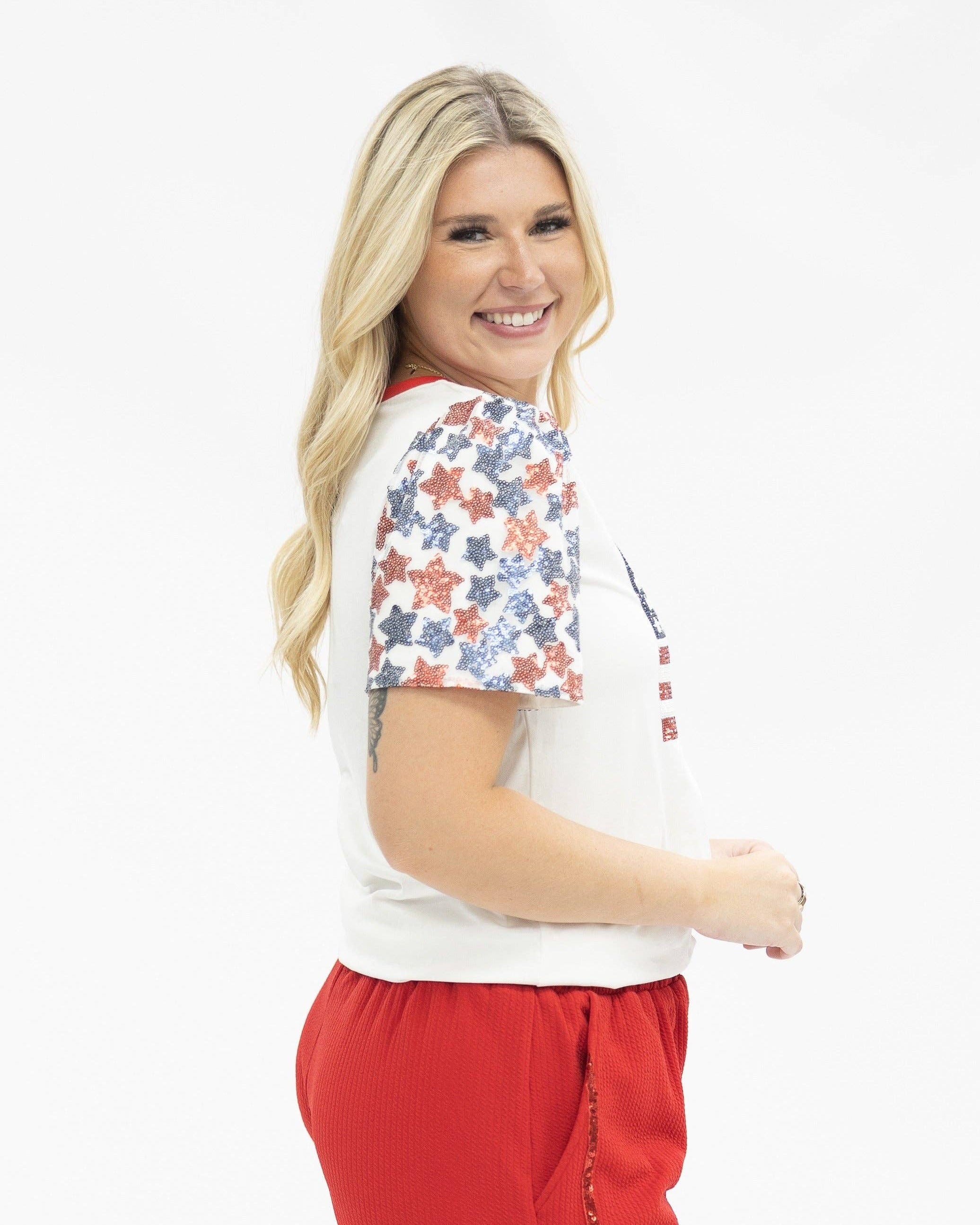 a high-stretch roomy-fit crew neck top with a sequin American flag front, lined star sleeves (red, white, and blue), red neckline trim, and a comfortable fit that runs large