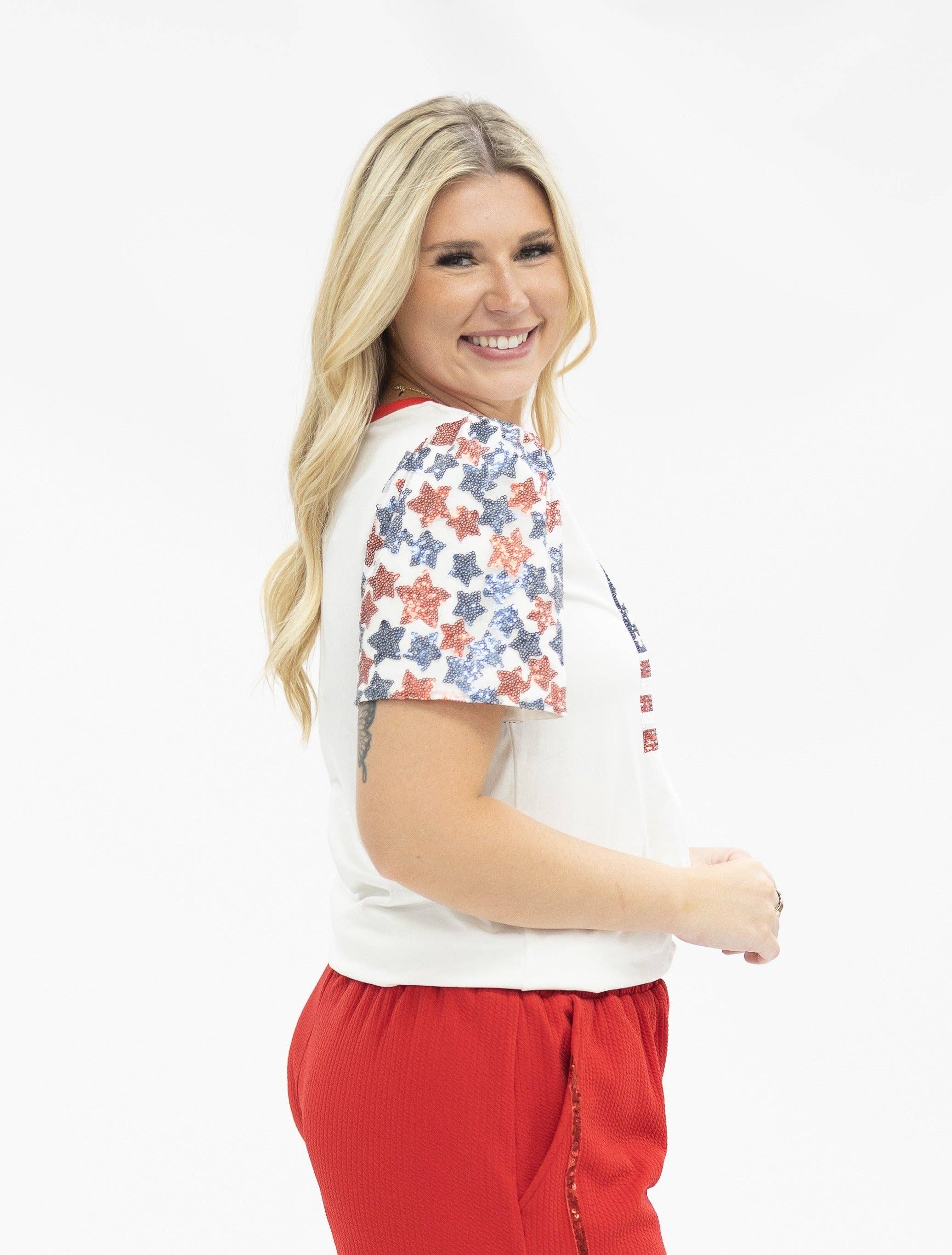 a high-stretch roomy-fit crew neck top with a sequin American flag front, lined star sleeves (red, white, and blue), red neckline trim, and a comfortable fit that runs large