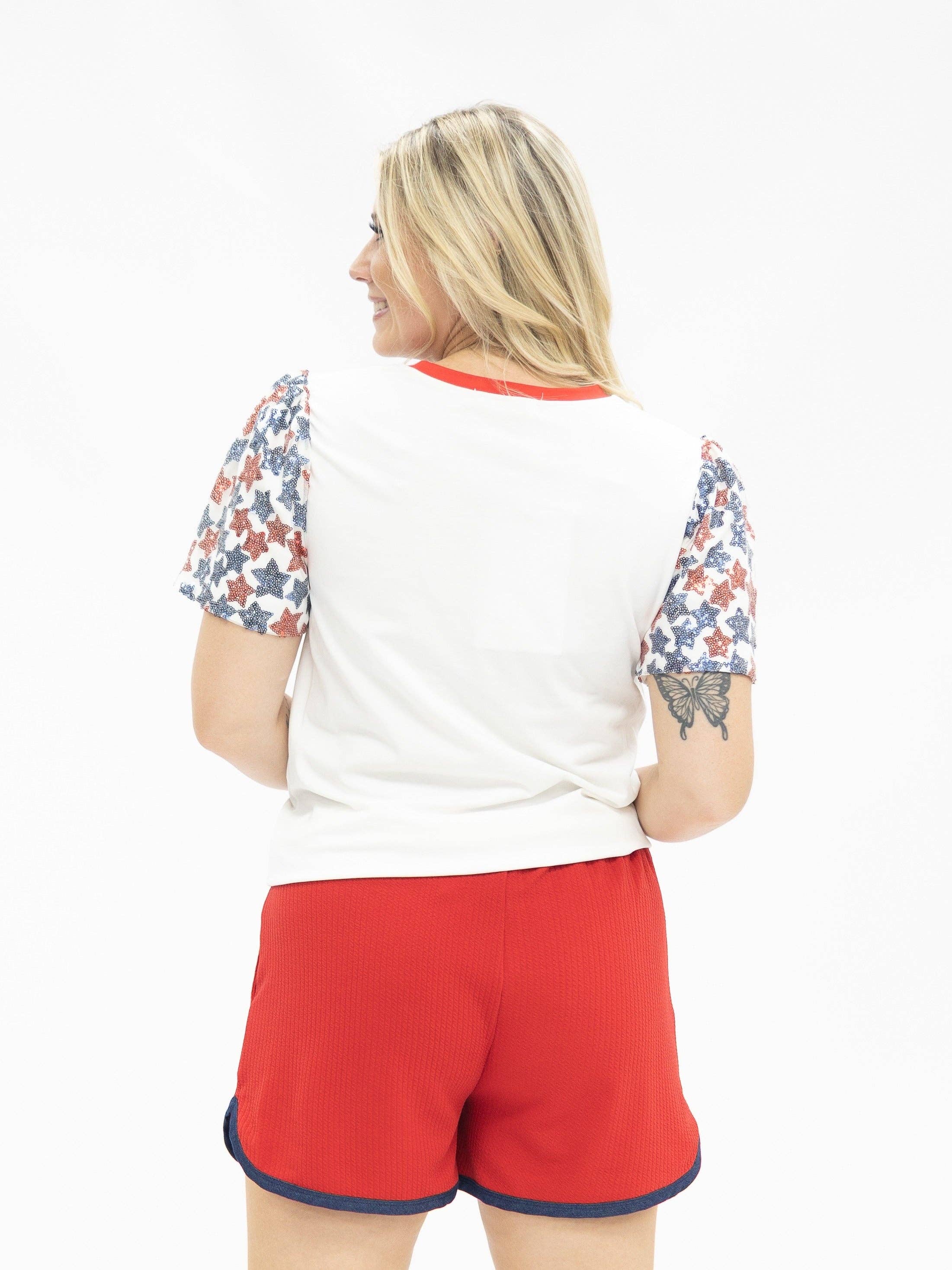 a high-stretch roomy-fit crew neck top with a sequin American flag front, lined star sleeves (red, white, and blue), red neckline trim, and a comfortable fit that runs large