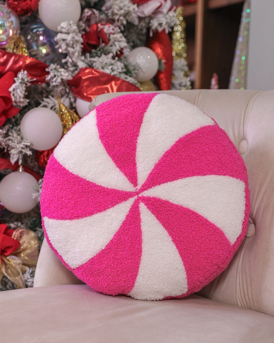 a round cushion with a bold hot pink and white peppermint swirl design on a soft, textured bouclé fabric