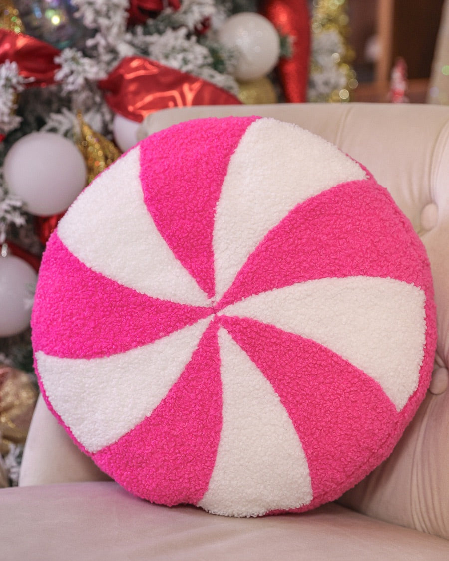 a round cushion with a bold hot pink and white peppermint swirl design on a soft, textured bouclé fabric