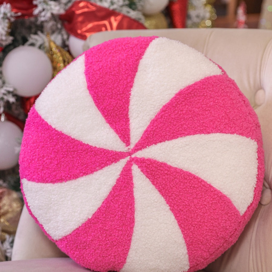 a round cushion with a bold hot pink and white peppermint swirl design on a soft, textured bouclé fabric
