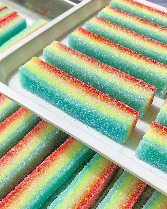 Colorful striped sour rainbow candy squishies on a white tray